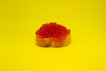 Side view of one red salmon caviar on yellow background