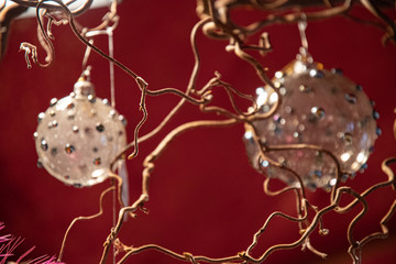 Christmas tree decoration on red background. Abstract background of blurry defocused crystal ornate balls and curly branches on foreground with red background. Creative backdrop. Unusual textures