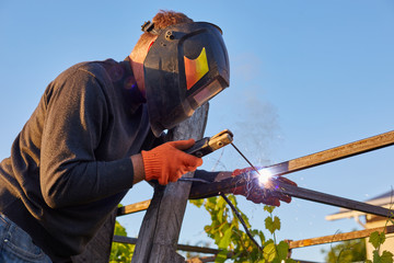 Male in face mask welds