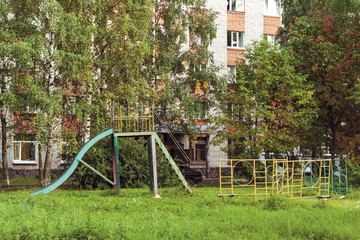 Fototapeta na wymiar summer landscape with an old metal children’s slide in a poor Russian town