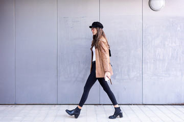 Pretty young woman walking while holding her mobile phone in the street.