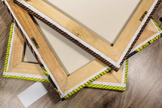 Wooden frames with stretched canvas and white blank card on a floor.