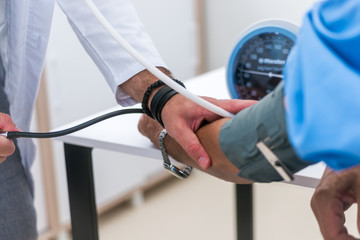A caucasian doctor measures the blood pressure of his senior patient.