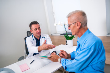 Patient and his doctor shake hands while the senior patient is leaving the doctor's office.