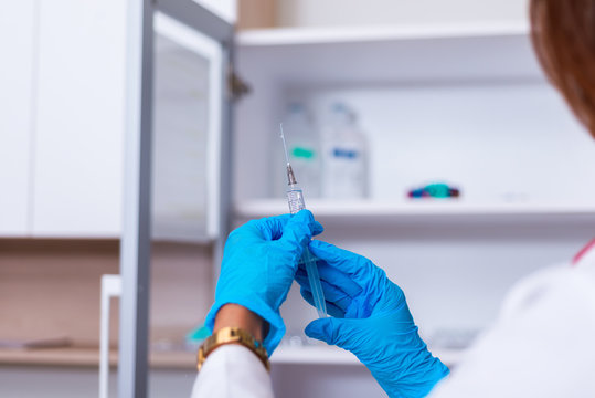 Close up od a female doctor ( nurse ) holding a syringe while standing in a medical office