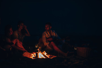 Obraz na płótnie Canvas Friends roasting sausage at the beach in the night