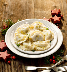 Christmas dumplings stuffed with mushroom and cabbage on a white plate on a rustic wooden table. Traditional Christmas eve dish in Poland