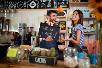 Business owner holding Open Sign. Man and woman  opening their store