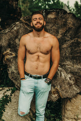 Handsome man with beard and sexy body posing outdoors