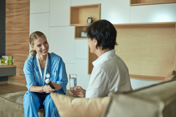 Obraz premium Beautiful smiling woman the doctor in a bottle of pill offers t