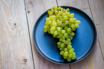 Branch of green grape raisins on a plate. Fruit on a plate. Green berries.