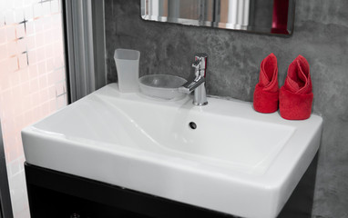 Modern stainless steel faucet with wash basin sink with a two red towels on it . Counter bathroom interior contemporary. Luxury and stylish design bathroom with a concrete style walls.