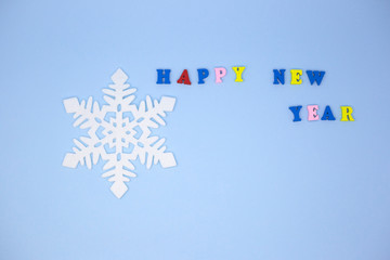 Felt snowflake on blue background next to inscription Happy New Year. Place for text. Greeting card