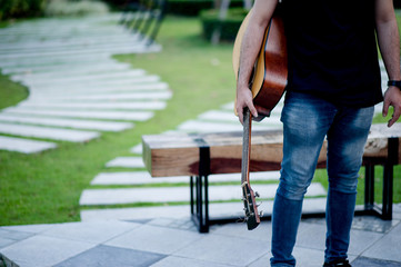 Picture of a guitarist, a young man playing a guitar while sitting in a natural garden,music concept