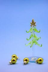Small model winter pine tree with golden balls on a blue background. Christmas atmosphere props