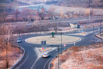 Streets and a roundabout with cars and a railroad in a frosty landscape