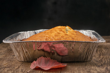 Side view of a baked pie in the form of thick aluminum foil on a wooden table