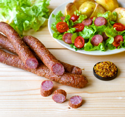 Smoked sausage with vegetables salad on a wooden board