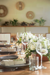The beautiful arrangement on the wooden table, white roses and ceramic plates. Boho chic wedding table setting.