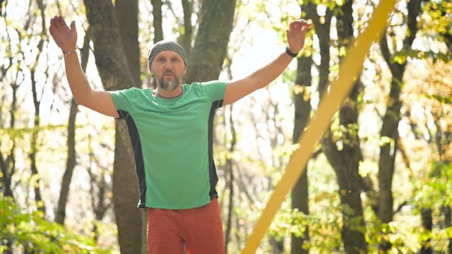 A Slack man aged with a beard in sportswear walks balancing on the slackline. The concept of sports activity at the age of 50. Athlete's foot closeup