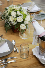 The beautiful arrangement on the wooden table, white roses and ceramic plates. Boho chic wedding table setting.