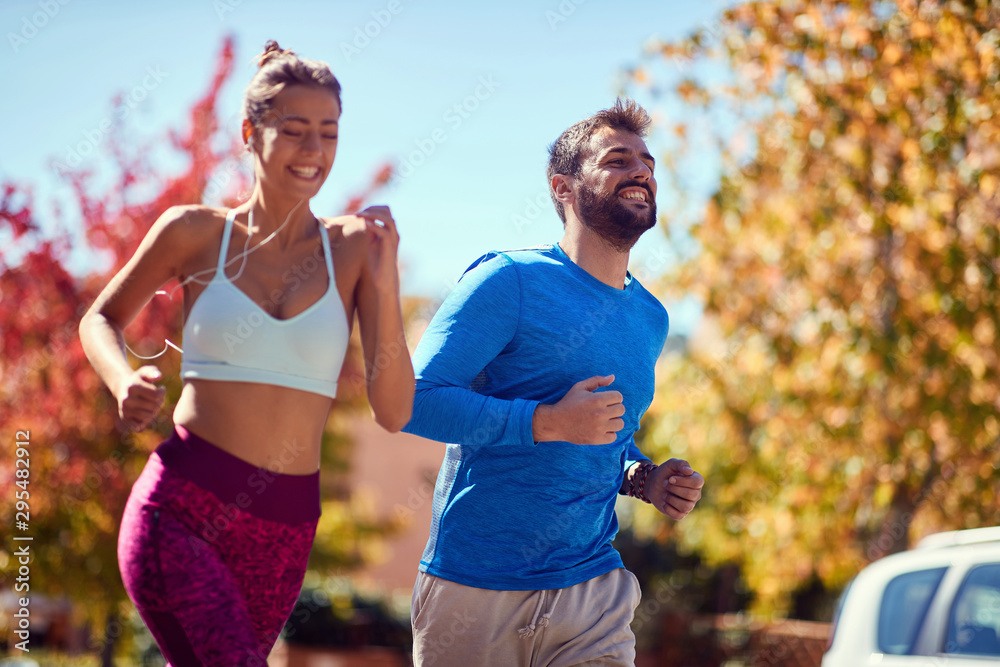 Wall mural young man and woman jogging at the park. healthy lifestyle. - Wall murals