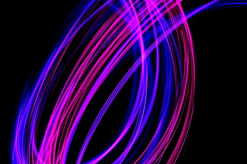 Long exposure photograph of neon pink and purple colour in an abstract swirl, parallel lines pattern against a black background. Light painting photography.