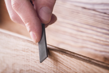 carpenter using  rasp or file handles wooden oak plank