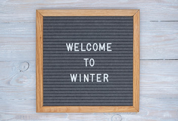 grey felt Board with English text welcome to winter. top view on wooden background