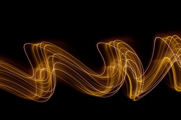 Long exposure photograph of neon colour in an abstract swirl, parallel lines pattern against a black background. Light painting photography.