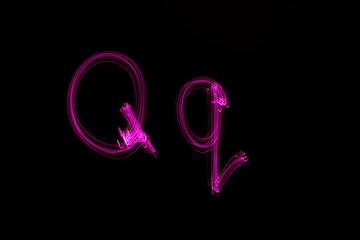 Long exposure photograph of  the letter q in pink neon color, in upper case and lower case, parallel lines pattern against a black background. Light painting photography.