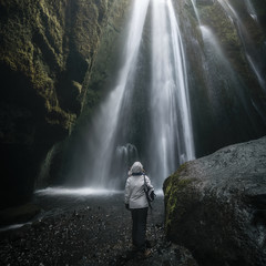 Woman looking at the Gljufrabui Waterdfall inside a cave in Iceland