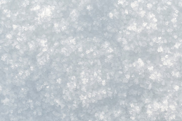 Macrophoto of fresh snowflakes and snow on the ground on a sunny day, good as a winter season background or texture in black and white.