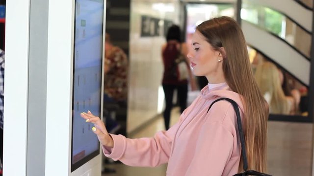 A woman orders food in the touch screen terminal with electronic menu in fast food restaurant