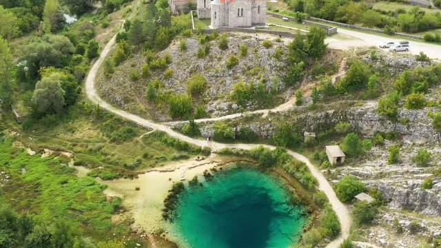Croatia, Cetina river source water hole and small Orthodox church in Dalmatian Zagora, aerial drone view, reveal shot