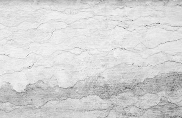 Close-up of an old, weathered and cracked stone wall. High resolution full frame textured background in black and white.