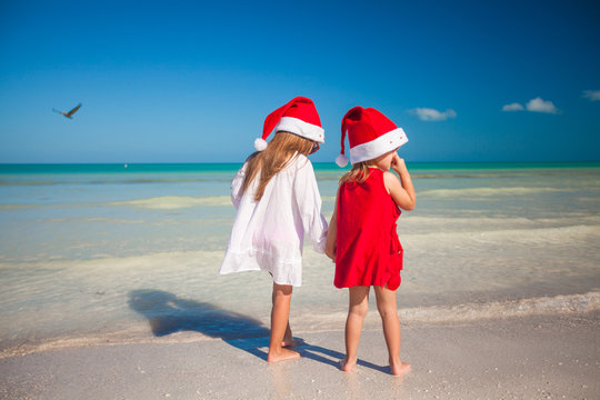 Rear view of Little cute girls in Christmas hats on the exotic beach