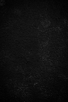 Close-up of a plastered, painted rough wall. Dark high resolution full frame textured background in black and white with vignetting.