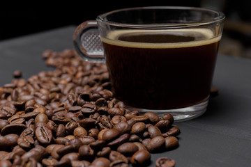 Coffee beans and cup of coffee on black painted background