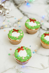 New Year's sweets on a marble table. Christmas cupcakes decorated with mastic and cream