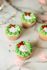 New Year's sweets on a marble table. Christmas cupcakes decorated with mastic and cream