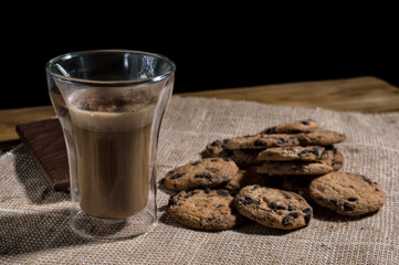 glass of cappuccino, chocolate and homemade cookies on burlap