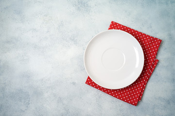 Empty white plate with tablecloth on gray stone table background.