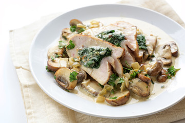 stuffed chicken breast fillet with spinach, mushrooms and a creamy gorgonzola sauce on a white plate