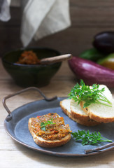Sandwich with eggplant caviar, eggplant spread, bread and vegetables on a wooden background. Rustic style.