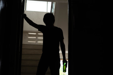 Silhouette of drunken man hold beer bottle walked into the old apartment are having stress in life and unable to find a solution and no advisor, from work problems And a failed family life.