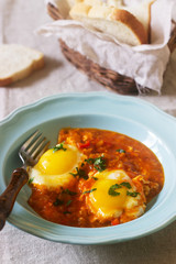 Shakshuka with bread on a wooden table. Middle eastern traditional dish. Homemade. Selective focus.