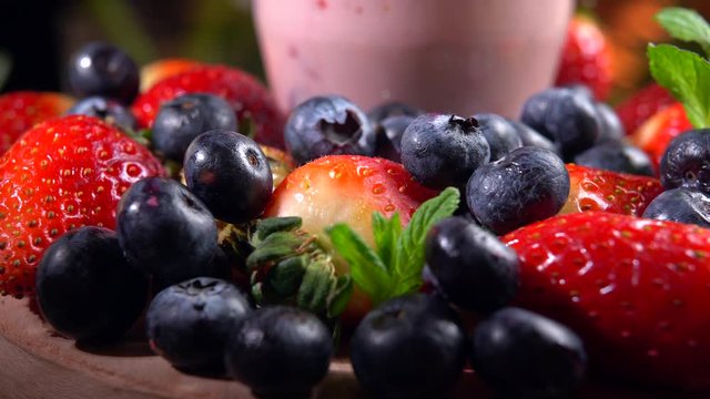 Fresh strawberry smoothie rotating on wooden plate. Nourishing milkshake 2in1 refreshing, vitamins and healthy eating. Mixed fruit for vegans, detox concept 