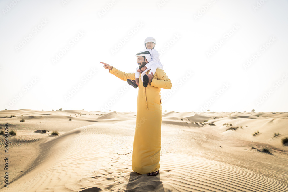 Wall mural Arabian man and son playing in the desert