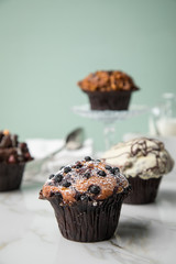 Muffin Auswahl mit Blaubeeren, Walnuss, Haselnuss und Weiße Schokolade mit Milch und Zucker für Kaffeepause auf Marmor Tisch und Grün Hintergrund